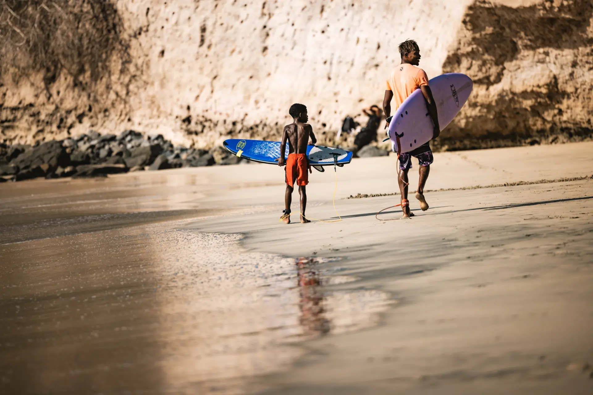 Kabungo and student walking with boards along cliffs