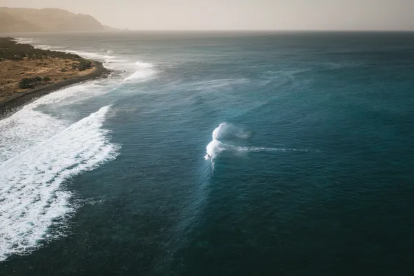 Aerial surfer carving the coastline